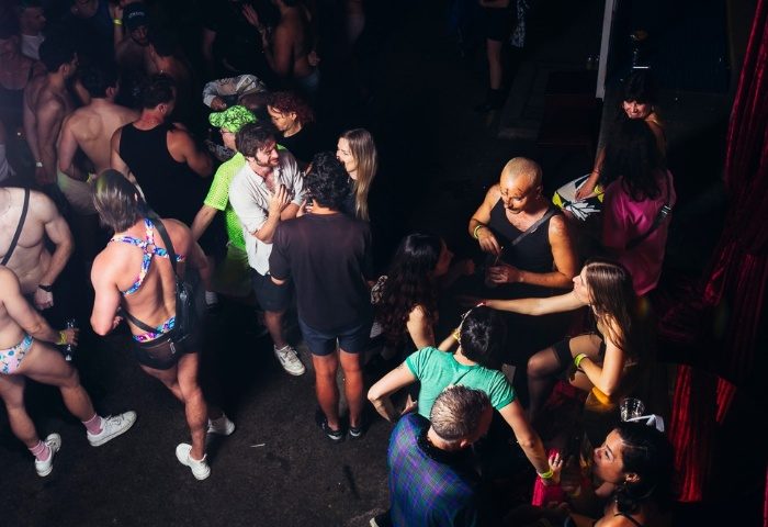 Crowd at House of Mince, Sydney. Gay men dance at a party. Nightlife scene with shirtless guys and people chatting. Gay travel.