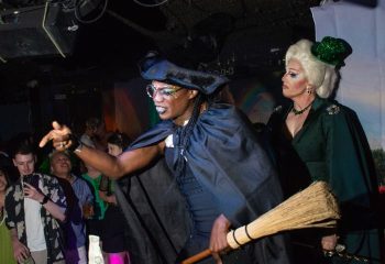 Drag queens at Hula's Bar in Honolulu. Gay bar with music, drinks, and leis. Performers in costume with a broom. Gay travel.