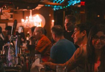 Hula's Bar and Lei Stand, a gay bar in Honolulu, Hawaii. People are enjoying drinks and music in a lively atmosphere. Gay travel advice.