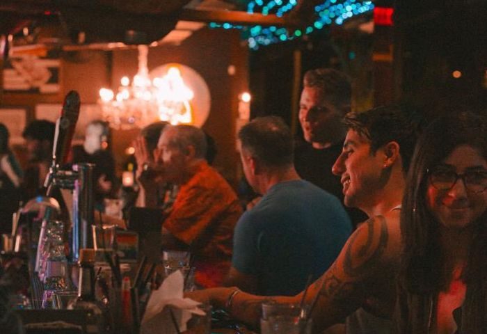 Hula's Bar and Lei Stand, a gay bar in Honolulu, Hawaii. People are enjoying drinks and music in a lively atmosphere. Gay travel advice.