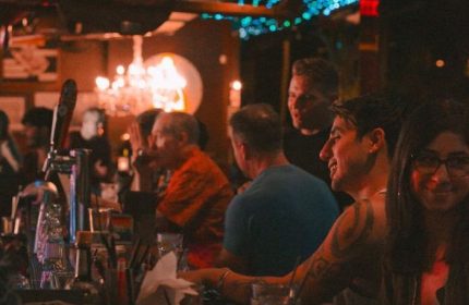 Hula's Bar and Lei Stand, a gay bar in Honolulu, Hawaii. People are enjoying drinks and music in a lively atmosphere. Gay travel advice.