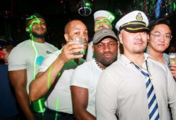 Group of gay men at a Shanghai club, enjoying nightlife. Diverse group with drinks, sailor hats, and fun. Gay travel advice, Shanghai nightlife.
