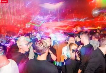 Shanghai gay nightlife: Crowded gay club scene with disco ball and colorful lights. Men socializing, enjoying drinks, and dancing.