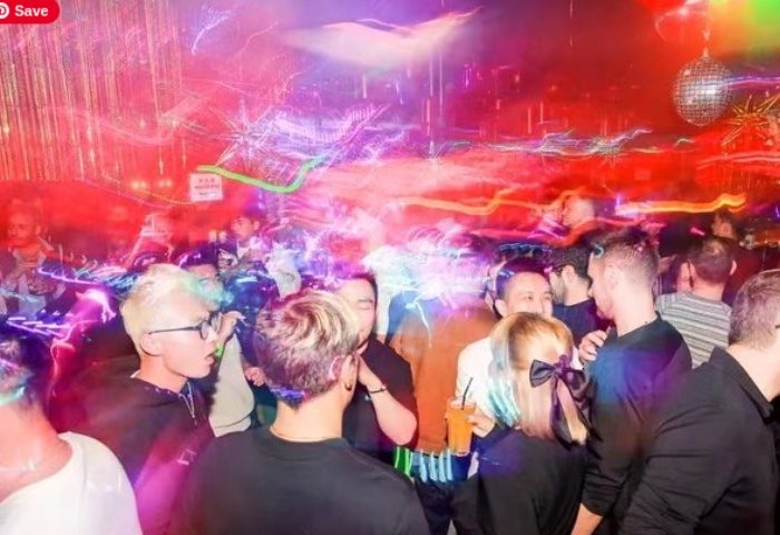 Shanghai gay nightlife: Crowded gay club scene with disco ball and colorful lights. Men socializing, enjoying drinks, and dancing.