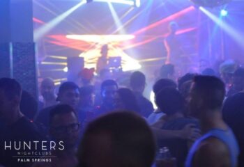 Hunters Nightclub dancefloor. Gay men dancing at Palm Springs' popular gay bar. Nightlife scene with DJ and colorful lights.