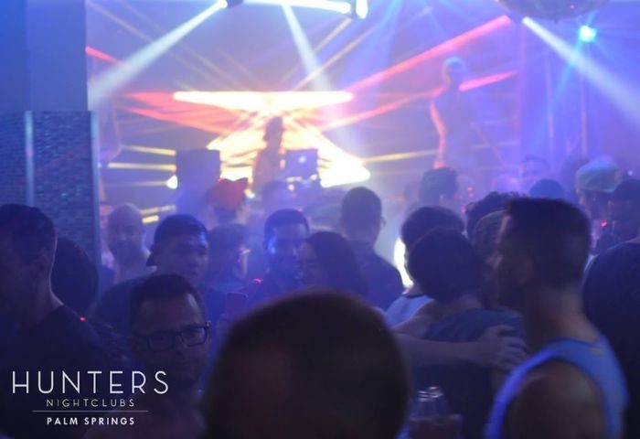Hunters Nightclub dancefloor. Gay men dancing at Palm Springs' popular gay bar. Nightlife scene with DJ and colorful lights.