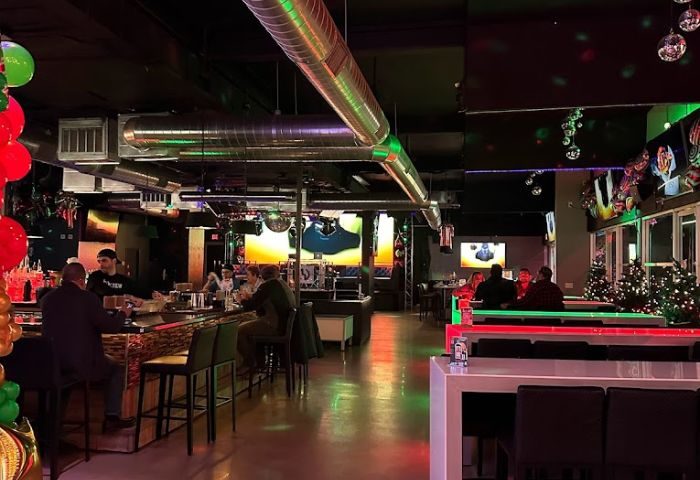 Hunters Nightclub Dine: Interior shot of the gay bar. People sit at the bar and tables. Disco balls and festive decorations.