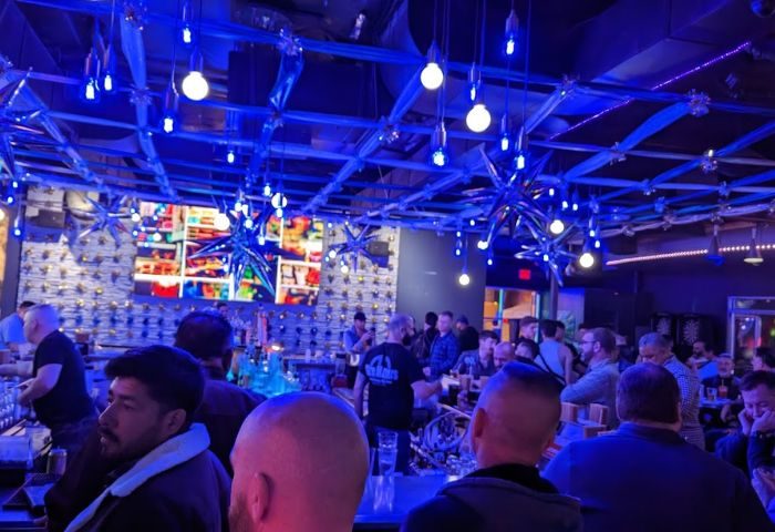 Interior of Hunters Nightclub, a gay bar. Men gather at the bar under blue lighting. Hunters-Nightclub.jpg. Gay travel advice.