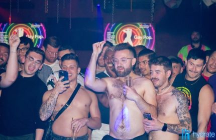 Gay men at Hydrate Nightclub, a popular gay bar in Chicago. Some are shirtless, dancing and drinking, with Gay Pop signs visible.