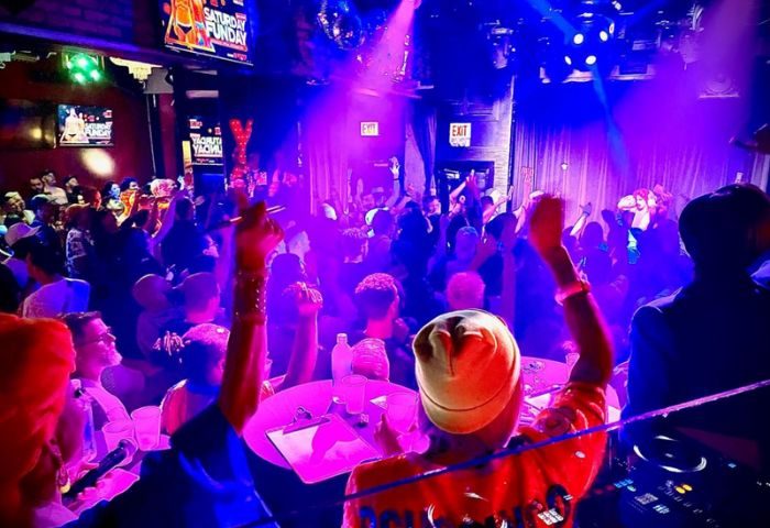 Hydrate Nightclub: Chicago gay bar with a drag show. Crowded dance floor under blue & purple lights. DJ plays music. Gay travel nightlife.
