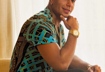 Stylish gay traveler posing with patterned shirt and gold watch. Gay travel advice for men, fashion inspiration.