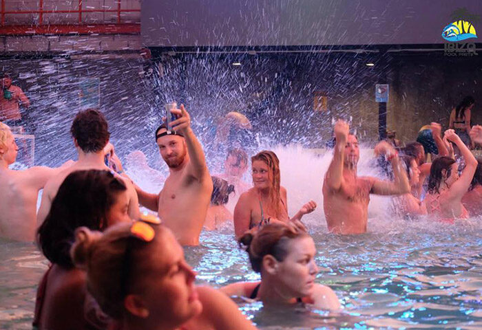 Ibiza House best gay party hotel. Koh Phi Phi beachfront pool party with shirtless men and women in the water, having fun with drinks.