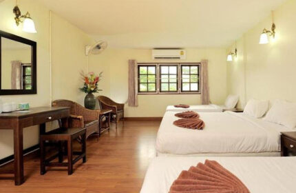 Phi Phi hotel room with three beds, desk, chairs, and a window. This cheap beachfront hotel is perfect for gay men traveling to Ibiza.