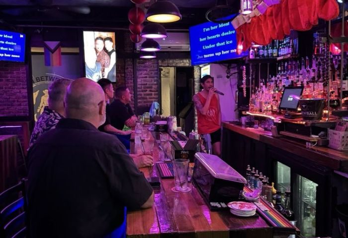 In-Between Waikiki gay bar karaoke in Honolulu. A man sings karaoke at a gay bar in Honolulu, Hawaii, with patrons at the bar.