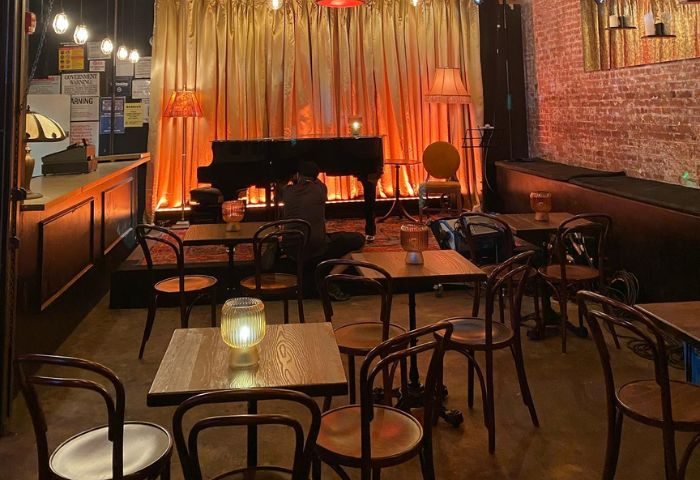 Interior of Industry Bar in New York. Stage with piano, tables, and chairs. Gay bar travel advice, nightlife.
