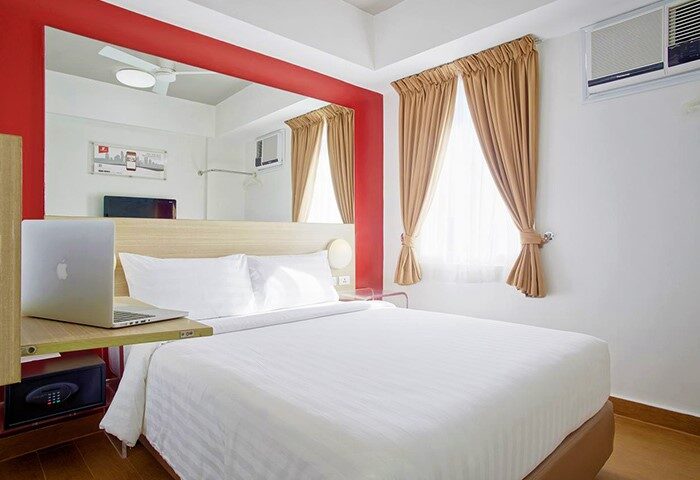 Red Planet Manila Makati hotel room. Modern, clean interior. Laptop on desk, safe below. Perfect central location for gay travelers.