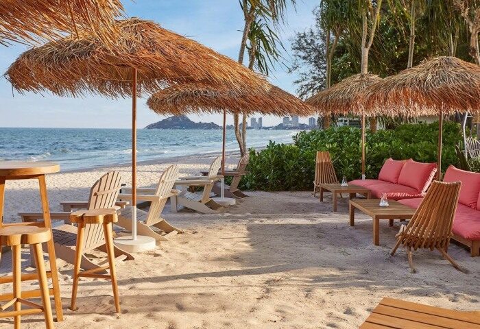 The Standard Hua Hin's beach. Gay beach holiday hotel with chairs, tables, and umbrellas on the sand. Instagram-perfect.