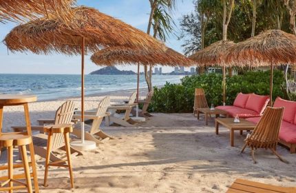 The Standard Hua Hin's beach. Gay beach holiday hotel with chairs, tables, and umbrellas on the sand. Instagram-perfect.