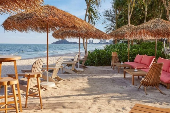 The Standard Hua Hin's beach. Gay beach holiday hotel with chairs, tables, and umbrellas on the sand. Instagram-perfect.