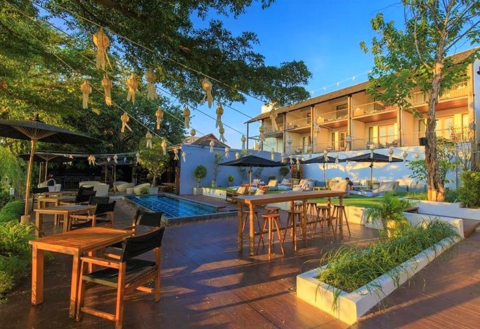 Sala Lanna Chiang Mai, an Instagram-perfect gay-friendly hotel. Outdoor dining area, pool, and stylish decor create a welcoming atmosphere.