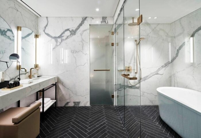 Academias Hotel, Autograph Collection: Luxurious bathroom with marble walls, glass shower, and herringbone floor. Gay hotels Athens travel advice.