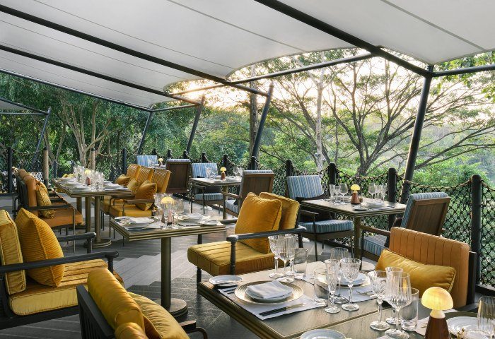 InterContinental Khao Yai Resort's outdoor dining area. Cool design hotel in the jungle. Tables are set for a meal with a view. Gay travel.