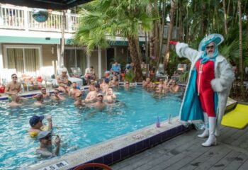 Island House Key West: A drag queen stands poolside at a gay resort. Men relax in the pool. Gay cruising, travel, and vacation.