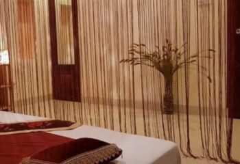 Jack Spa Ho Chi Minh: Room detail with string curtains, bed, and vase with plant. Gay travel advice for Vietnam spa experience.