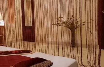 Jack Spa Ho Chi Minh: Room detail with string curtains, bed, and vase with plant. Gay travel advice for Vietnam spa experience.