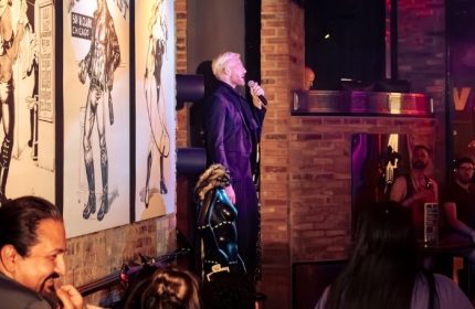 Singer performing at Jackhammer, a gay bar party in Chicago. The venue features brick walls and leather art. Nightlife scene.