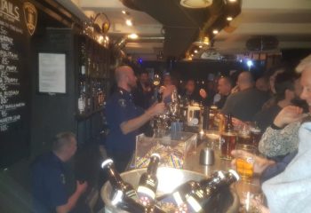 Jailhouse CPH bar in Copenhagen. Bartender in uniform serves drinks to patrons. Gay travel advice for a unique bar experience in Denmark.