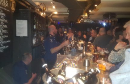Jailhouse CPH bar in Copenhagen. Bartender in uniform serves drinks to patrons. Gay travel advice for a unique bar experience in Denmark.