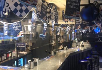 Jailhouse CPH Copenhagen: Interior of a gay bar decorated for Christmas with Tuborg beer banners. Bar stools line the counter in this gay travel spot.