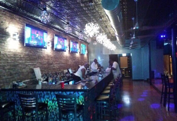 Interior of Jeffery Pub, a gay bar in Chicago, featuring a bar with TVs, patrons, and decorative lighting. Gay travel.