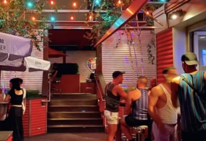 Outdoor patio at Jeffery Pub, a gay bar in Chicago. Men socialize under colorful lights. Gay travel destination.