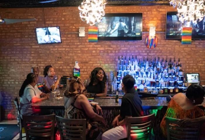 Interior of Jeffery Pub, a popular gay bar in Chicago. Patrons sit at the bar with rainbow decorations.