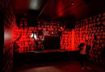 Interior of Jolene's Queer Bar in San Francisco, a gay travel destination. Red lighting, stage, and wallpaper with torso images.