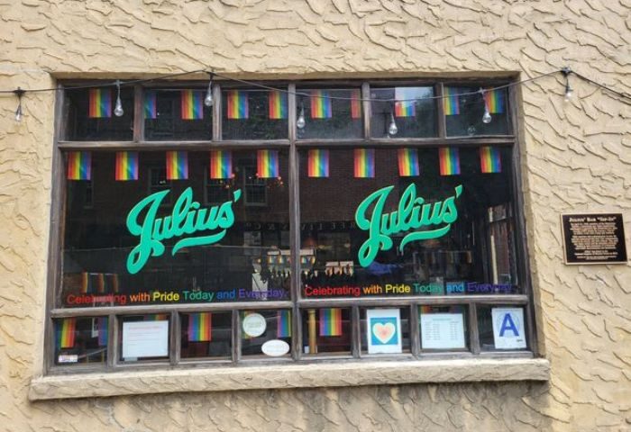 Julius' Gay Bar in New York window view. Rainbow flags decorate the famous gay bar, a historic landmark for gay men travel.