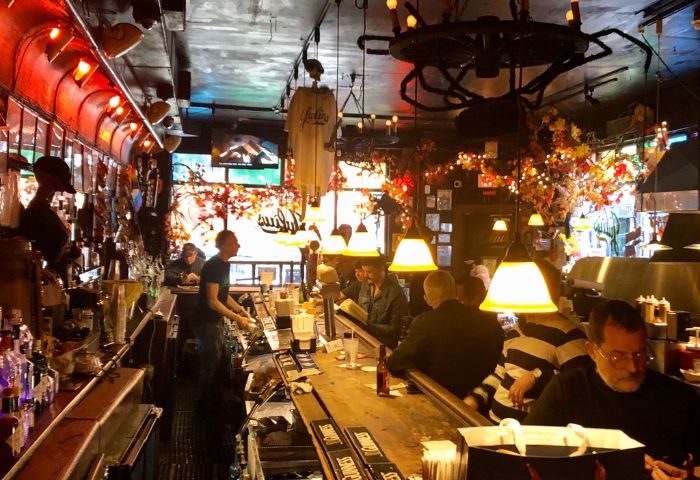 Interior view of Julius' Gay Bar in New York. People at the bar, vintage decor, and a lively atmosphere. Gay men travel destination.