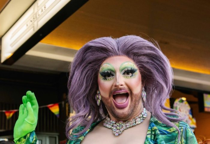 Drag queen at Kinselas Bar, Sydney. Gay travel advice, nightlife. Purple wig, green gloves, rainbow flags.