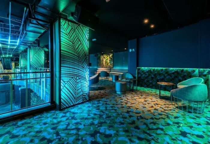 Kluster @ REBEL Gay Club in Madrid. Interior view of the lounge area with tropical decor and blue lighting. Gay nightlife travel.