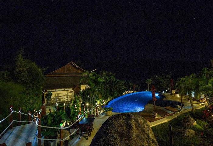 Night view of Koh Phangan Pavilions, a cheap gay hotel in Koh Phangan, Thailand. Rooftop pool is visible. Gay travel destination.