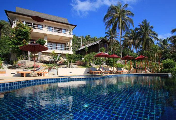 Koh Phangan Pavilions LGBT popular choice hotel. Poolside view of this gay-friendly resort in Thailand with palm trees and sunny sky.