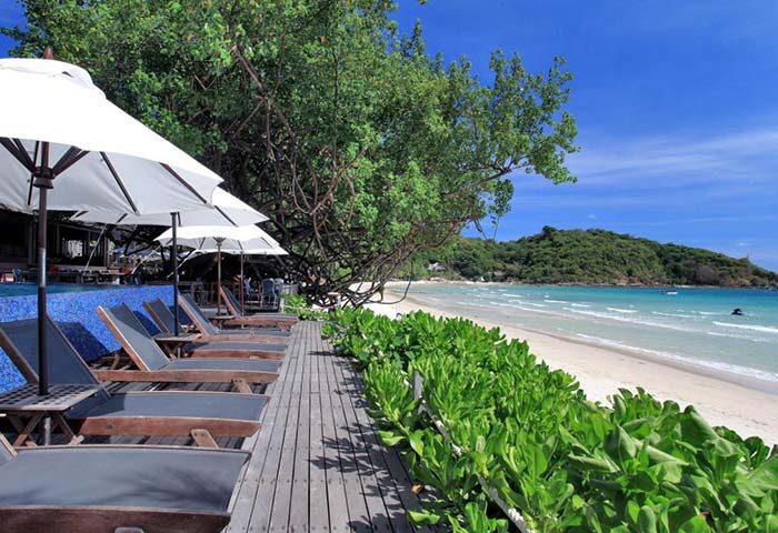 Ao Prao Resort, Koh Samet gay-friendly hotel. Beachfront view with lounge chairs, umbrellas, and lush greenery. Ideal for gay men's travel.