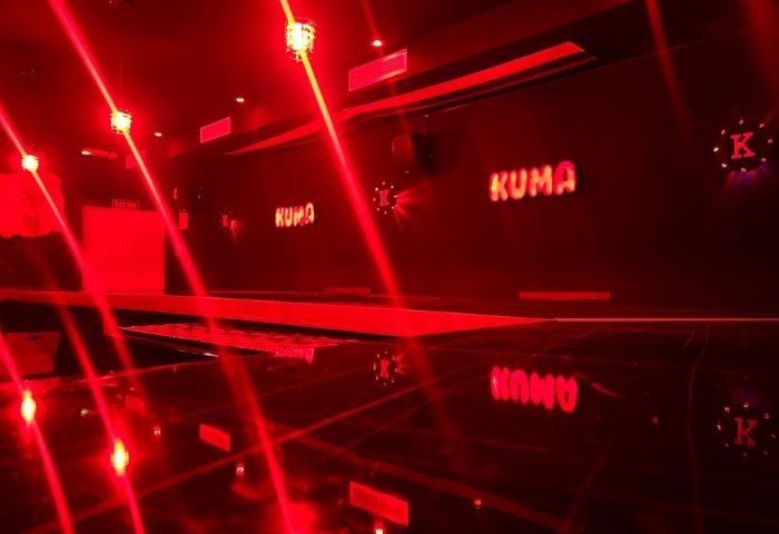 Kuma Bar in Benidorm. Interior shot of gay bar with red lighting and Kuma logo. Nightlife party scene for gay men travel in Spain.
