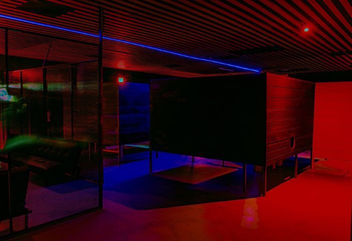 Interior of Kuma Club, a gay bathhouse in Las Vegas. Features include private rooms, a lounge area, and colorful red and blue lighting.