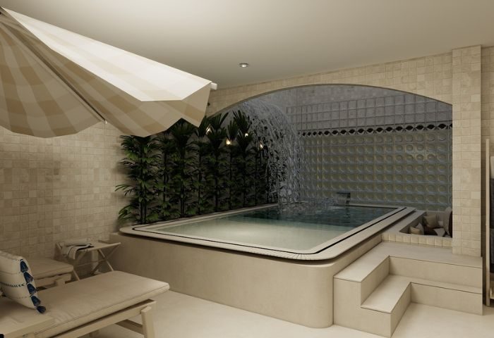 Kuma Club Las Vegas gay bathhouse: An indoor pool with a waterfall feature and a sun umbrella, offering a relaxing spa experience.