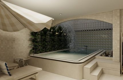 Kuma Club Las Vegas gay bathhouse: An indoor pool with a waterfall feature and a sun umbrella, offering a relaxing spa experience.