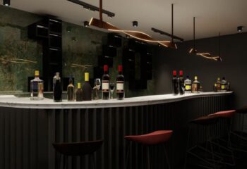 Kuma Club bar interior, Las Vegas gay bathhouse. Liquor bottles line the counter. Stylish lighting. Dark, modern design. Gay travel.