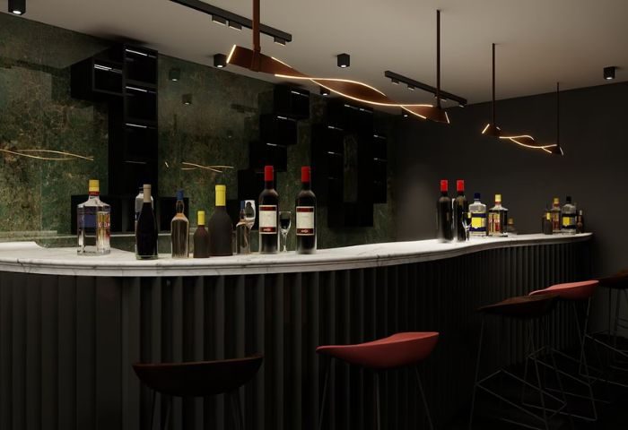 Kuma Club bar interior, Las Vegas gay bathhouse. Liquor bottles line the counter. Stylish lighting. Dark, modern design. Gay travel.